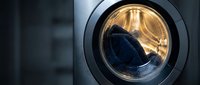 Modern washing machine drum with warm golden lighting showcasing clean laundry care technology for home appliance and household maintenance concepts.