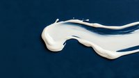 White liquid splash wave on dark blue background, dynamic fluid motion with glossy texture and smooth curves creating abstract artistic composition.