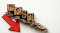 Wooden letter blocks spelling COST with red arrow pointing down over scattered coins, representing expense reduction and financial savings concept.