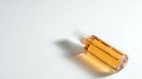Amber glass dropper bottle with golden serum on white background, isolated cosmetic packaging for skincare and beauty product design applications.