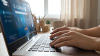 Professional woman hands typing on laptop computer with financial data charts and graphs on screen for business analysis and investment planning in modern office workspace.