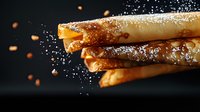 Crispy rolled wafer cookies dusted with powdered sugar against dark background, falling sugar particles create dynamic food composition for dessert menu.