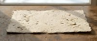 Handmade paper sheet with natural texture and rough edges on wooden surface for craft projects and artistic applications.