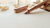 Elegant rose gold fountain pen on white paper with soft lighting for luxury writing and calligraphy projects.