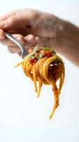Hot steaming spaghetti pasta with tomato sauce and fresh herbs twirled on fork held by hand against white background for culinary and restaurant use.