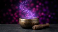 Antique brass singing bowl with wooden mallet releasing magical purple sparkles and cosmic energy for meditation, sound healing and spiritual practices.