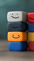 Colorful stacked blocks with happy smiling faces drawn on them against blurred background. Concept of positive emotions, friendship and teamwork.