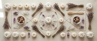 Flat lay arrangement of lavender bundles, white meringues and purple crystals in geometric pattern on neutral background for spa and wellness designs.