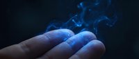 Blue mystical smoke rising from open palm against dark background creating magical atmosphere for fantasy and supernatural concepts.