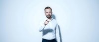 Confident Caucasian businessman in white shirt pointing finger at camera on light background, expressing authority and direct communication.