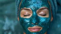 Young Caucasian woman with closed eyes wearing glittering turquoise facial mask. Luxury spa skincare and beauty treatment concept showing self-care routine.