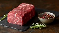 Raw beef steak on slate board with rosemary herbs and peppercorns for gourmet cooking and culinary preparation on dark wooden background.