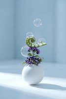 Soap bubbles floating above purple flowers in white ceramic vase on clean minimalist background for spa wellness and relaxation concepts.