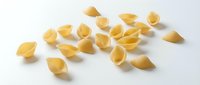 Scattered golden pasta shells on white background, isolated for culinary design, food packaging, and recipe content.