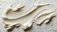 Creamy white frosting texture with smooth swirls and peaks creates dynamic movement across surface, macro photography shows rich detail and depth in soft lighting.