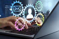 Business automation concept with hands typing on laptop and colorful gear icons representing CRM, email marketing, analytics and advertising integration.