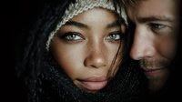 Young mixed-race woman and Caucasian man in winter clothing sharing intimate moment with warm lighting and cozy atmosphere for lifestyle photography.