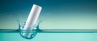 White cosmetic bottle splashing into clear turquoise water with dynamic splash effect against gradient blue background for skincare and beauty product advertising.