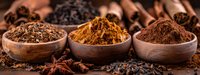 Aromatic spices in wooden bowls featuring cinnamon, turmeric, and cocoa powder with star anise and scattered spices on dark rustic background, perfect for culinary and food design.