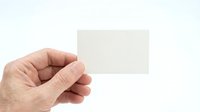Male hand holding blank white business card mockup against clean background for corporate branding and contact information display.
