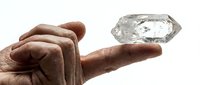 Male hand with medium-dark skin tone holding a raw crystal or mineral specimen, isolated on white background for design and educational use.