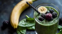 Green smoothie bowl topped with fresh blackberries and banana slices, served with a straw. Healthy breakfast or nutritious drink for wellness and diet concepts.