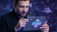 Professional businessman examining digital healthcare technology interface with magnifying glass on futuristic blue background for medical innovation concepts.