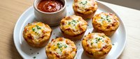 Golden baked egg muffins with cheese and herbs served on white plate with tomato sauce dip, perfect breakfast or brunch appetizer for meal prep.