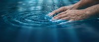 Male hand touching calm blue water surface creating ripples, suitable for wellness, spa, relaxation, and aquatic lifestyle concepts.