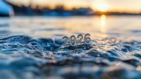 Metallic 2026 numbers floating on rippling water surface at sunset, golden sun reflection creates magical atmosphere. For New Year designs and calendars.