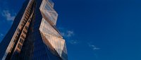 Modern glass skyscraper with twisted architectural design against blue sky. Contemporary urban development and commercial real estate concept.