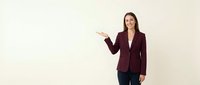 Professional businesswoman in burgundy blazer presenting with open palm gesture on neutral background for corporate presentations and marketing materials.