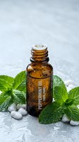 Peppermint essential oil bottle with fresh mint leaves and water droplets on marble surface for aromatherapy and natural wellness treatments.