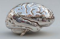 Metallic chrome brain with urban cityscape reflection showing buildings and streets in polished surface for medical technology and neuroscience concepts.