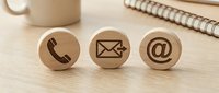 Contact us symbols on wooden spheres with phone, email and at sign icons for business communication and customer service.