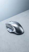 Silver ergonomic computer mouse on concrete surface with minimalist blue-gray background, suitable for tech product marketing, web design, and business presentations.