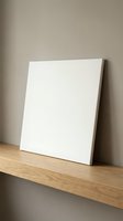 Blank white canvas on wooden shelf against neutral wall ready for artwork display in modern minimalist interior space for creative projects.