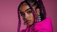 Young African American woman with pink braids and crystal earrings wearing vibrant fuchsia hoodie against purple background, fashion beauty portrait with creative styling.