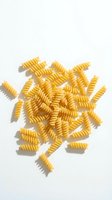 Scattered golden spiral pasta shapes arranged on white background with natural shadows, ready for food, cooking, and culinary design projects.