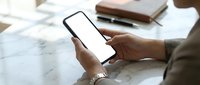 Professional businesswoman holding smartphone with blank white screen at marble desk workspace for mobile app mockup and digital communication.