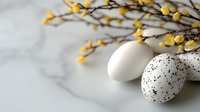 Speckled and white decorative eggs with yellow spring flowers on marble background, minimalist Easter composition with negative space.