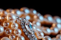 Elegant pearl necklace with vintage crystal brooch on dark background, macro shot highlighting luxury jewelry details and soft romantic lighting effects.