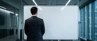 Professional businessman in dark suit standing before large blank white presentation screen in modern glass conference room for corporate meetings.