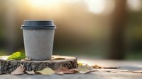 Takeaway coffee cup on wooden stump surrounded by autumn leaves at sunset, creating cozy atmosphere for seasonal beverage marketing and cafe promotion.