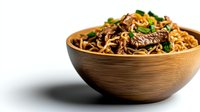 Asian stir-fried noodles with beef strips, mushrooms and green onions served in wooden bowl on white background, selective focus with copy space.