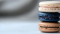 Stack of colorful French macarons with pink, blue and brown flavors on white surface. Sweet dessert cookies for bakery, cafe menu or culinary photography.