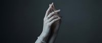 Elegant female hands with manicured nails and delicate bracelet against dark background for beauty and skincare concepts.