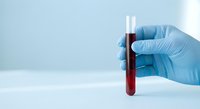 Hand in blue latex glove holding test tube with blood sample in laboratory, medical diagnostics and healthcare research concept.