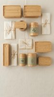 Flat lay arrangement of eco-friendly bamboo storage boxes, natural linen pouches tied with twine, and wooden containers with leaf designs on neutral background for sustainable lifestyle content.