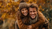 Happy couple embracing in autumn park wearing cozy knit sweaters and warm clothing during golden fall season with colorful foliage background for lifestyle content.